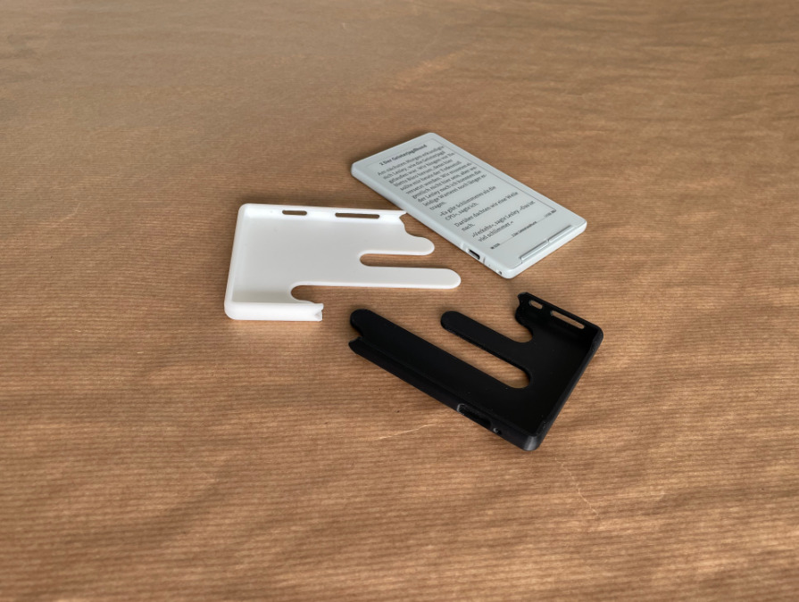 Two-part 3D printed Xteink X4 case shown in black and white PLA beside the device.