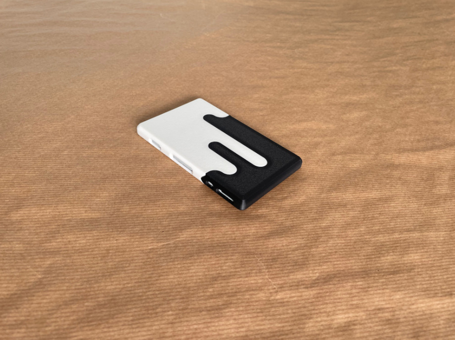 Assembled black and white 3D printed Xteink X4 case on a wooden surface.